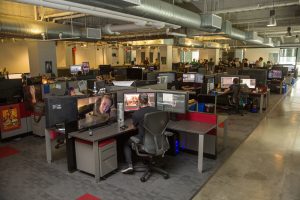 Developers work at rows of desks and monitors on the open studio floor at Naughty Dog.
