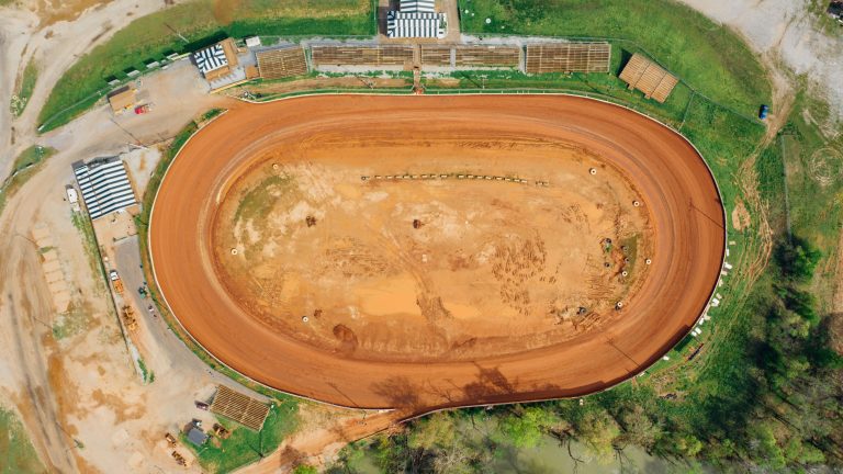 dirt oval racing track with small grandstand