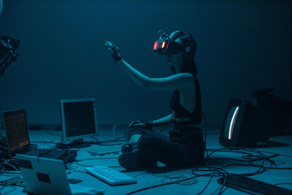 Woman immersed in virtual reality, surrounded by tech, in a dimly lit room