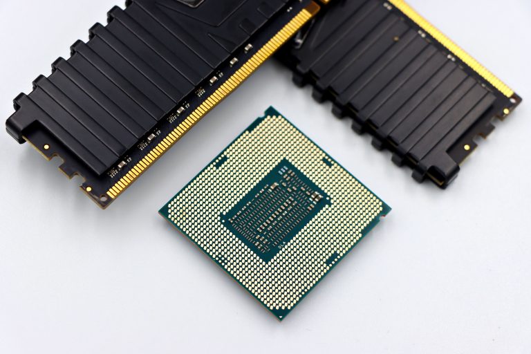 A CPU and RAM sticks displayed on a white surface, showcasing computer hardware components